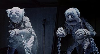 Movie still from “The Muppet Christmas Carol” (1992), directed by Brian Henson – A couple of people that are chained to a wall; Medium shot, Low angle