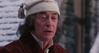 Movie still from “The Muppet Christmas Carol” (1992), directed by Brian Henson – An older man wearing a white hat and a red jacket; Close Up shot, Over the shoulder angle