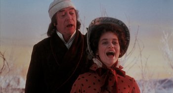 Movie still from “The Muppet Christmas Carol” (1992), directed by Brian Henson – An older man and a young woman in a red dress; Medium shot, Low angle