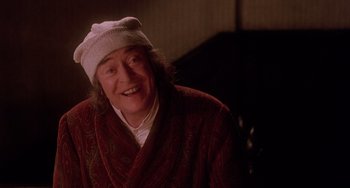 Movie still from “The Muppet Christmas Carol” (1992), directed by Brian Henson – An older woman wearing a robe and a white hat; Close Up shot, Over the shoulder angle