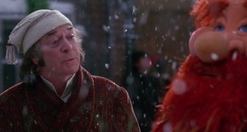 Movie still from “The Muppet Christmas Carol” (1992), directed by Brian Henson – An old man wearing a red hat and a red coat; Close Up shot, Over the shoulder angle