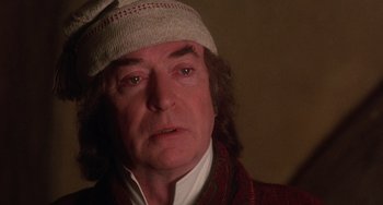 Movie still from “The Muppet Christmas Carol” (1992), directed by Brian Henson – An older man wearing a hat and looking at the camera; Close Up shot, Over the shoulder angle