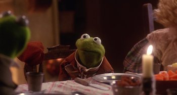 Movie still from “The Muppet Christmas Carol” (1992), directed by Brian Henson – A stuffed frog sitting at a table; Medium shot, Over the shoulder angle