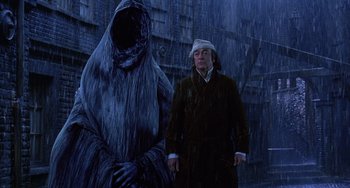 Movie still from “The Muppet Christmas Carol” (1992), directed by Brian Henson – A man standing in front of a giant creature; Medium shot, Low angle