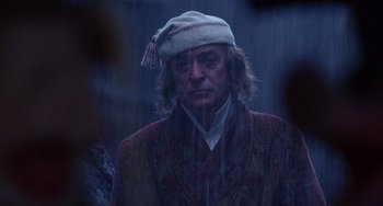 Movie still from “The Muppet Christmas Carol” (1992), directed by Brian Henson – A man in a hat and a robe in the rain; Close Up shot, Over the shoulder angle