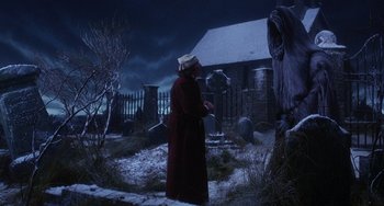Movie still from “The Muppet Christmas Carol” (1992), directed by Brian Henson – An old woman standing in the snow next to an old grave; Wide shot, Low angle