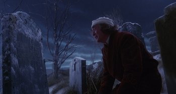 Movie still from “The Muppet Christmas Carol” (1992), directed by Brian Henson – An old man in a red jacket is looking at a grave; Medium shot, Over the shoulder angle