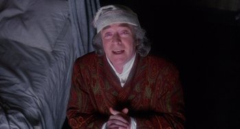 Movie still from “The Muppet Christmas Carol” (1992), directed by Brian Henson – An older woman wearing a white hat and a red robe; Medium shot, Low angle