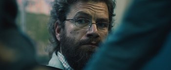 Movie still from “Riders of Justice” (2020), directed by Anders Thomas Jensen – A person with a beard wearing glasses; Close Up shot, Over the shoulder angle