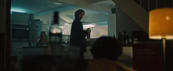 Movie still from “Riders of Justice” (2020), directed by Anders Thomas Jensen – A man standing in front of a counter holding a drink; Medium shot, Low angle