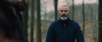 Movie still from “Riders of Justice” (2020), directed by Anders Thomas Jensen – A man with a gray beard standing in the woods; Close Up shot, Low angle