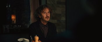 Movie still from “Riders of Justice” (2020), directed by Anders Thomas Jensen – A man sitting at a table in front of a chess board; Close Up shot, Over the shoulder angle