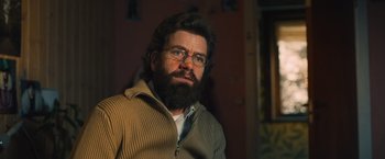 Movie still from “Riders of Justice” (2020), directed by Anders Thomas Jensen – A man with a beard wearing glasses and a sweater; Close Up shot, Low angle