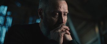 Movie still from “Riders of Justice” (2020), directed by Anders Thomas Jensen – A person with his hands under his chin; Close Up shot, Low angle