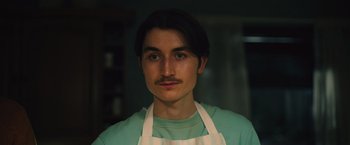 Movie still from “Riders of Justice” (2020), directed by Anders Thomas Jensen – A man with a mustache wearing an apron; Close Up shot, Low angle