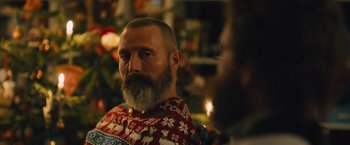 Movie still from “Riders of Justice” (2020), directed by Anders Thomas Jensen – A man with a gray beard wearing a christmas sweater; Close Up shot, Over the shoulder angle