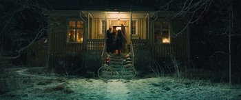 Movie still from “Riders of Justice” (2020), directed by Anders Thomas Jensen – A bicycle parked in front of a house with people standing on the steps; Extreme Wide shot, High angle