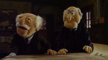 Movie still from “The Muppets” (2011), directed by James Bobin – A couple of puppets sitting next to each other on top of a table; Medium shot, Low angle