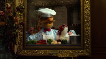 Movie still from “The Muppets” (2011), directed by James Bobin – A man in a chef's outfit holding a pan with a chicken on top of it; Medium shot, Low angle