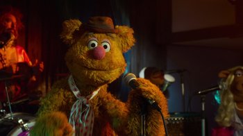 Movie still from “The Muppets” (2011), directed by James Bobin – A brown teddy bear wearing a brown hat and a tie; Close Up shot, Over the shoulder angle