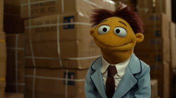 Movie still from “The Muppets” (2011), directed by James Bobin – A man in a suit and tie standing in front of boxes; Close Up shot, Low angle