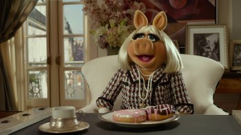 Movie still from “The Muppets” (2011), directed by James Bobin – A woman sitting in front of a plate of doughnuts; Medium shot, High angle