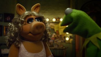 Movie still from “The Muppets” (2011), directed by James Bobin – A woman in a pink dress is looking at a green bird; Close Up shot, Over the shoulder angle