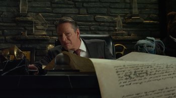Movie still from “The Muppets” (2011), directed by James Bobin – A man sitting at a desk looking at a piece of paper on top of a desk; Medium shot, High angle