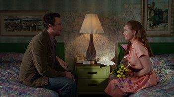 Movie still from “The Muppets” (2011), directed by James Bobin – A man and a woman sitting on a bed next to a lamp; Medium shot, High angle