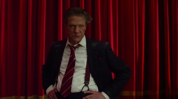 Movie still from “The Muppets” (2011), directed by James Bobin – A man in a suit and tie standing in front of a red curtain; Medium shot, Low angle
