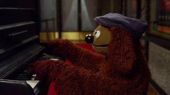 Movie still from “The Muppets” (2011), directed by James Bobin – A stuffed animal wearing a hat playing the piano; Close Up shot, High angle