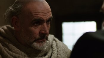 Movie still from “The Name of the Rose” (1986), directed by Jean-Jacques Annaud – An older man with a beard looking at the camera; Close Up shot, Low angle