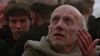 Movie still from “The Name of the Rose” (1986), directed by Jean-Jacques Annaud – An old man with a bald head looking up at the sky; Close Up shot, Low angle