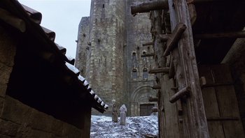 Movie still from “The Name of the Rose” (1986), directed by Jean-Jacques Annaud – A man standing in front of an old building; Extreme Wide shot, Low angle