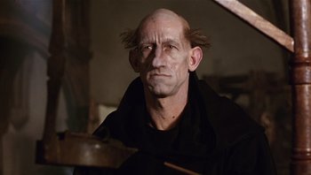 Movie still from “The Name of the Rose” (1986), directed by Jean-Jacques Annaud – A man with a bald head is looking at the camera; Close Up shot, Low angle