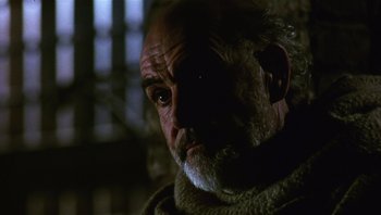 Movie still from “The Name of the Rose” (1986), directed by Jean-Jacques Annaud – An old man with a beard looking at the camera; Close Up shot, Low angle