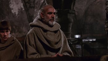 Movie still from “The Name of the Rose” (1986), directed by Jean-Jacques Annaud – An older man in a monk's robe sitting in a room; Medium shot, Low angle