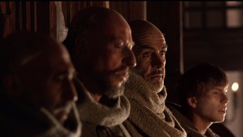Movie still from “The Name of the Rose” (1986), directed by Jean-Jacques Annaud – A group of men sitting next to each other in a room; Close Up shot, Low angle