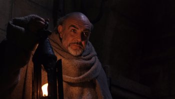Movie still from “The Name of the Rose” (1986), directed by Jean-Jacques Annaud – An older man with a beard and a scarf around his neck; Close Up shot, Low angle