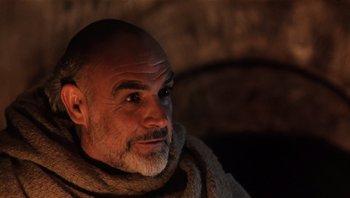 Movie still from “The Name of the Rose” (1986), directed by Jean-Jacques Annaud – An older man with a beard and a scarf around his neck; Close Up shot, Low angle