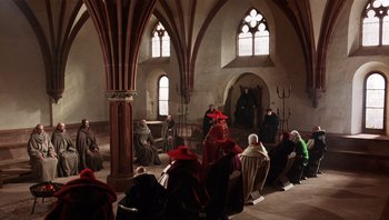 Movie still from “The Name of the Rose” (1986), directed by Jean-Jacques Annaud – A group of people sitting in a room; Wide shot, High angle