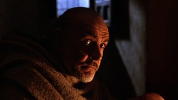 Movie still from “The Name of the Rose” (1986), directed by Jean-Jacques Annaud – A man with a beard and a towel around his neck; Close Up shot, Low angle