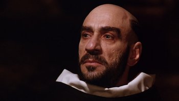 Movie still from “The Name of the Rose” (1986), directed by Jean-Jacques Annaud – A bald man with a beard and a white collar; Close Up shot, Low angle
