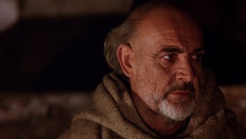 Movie still from “The Name of the Rose” (1986), directed by Jean-Jacques Annaud – An older man with a beard and a sweater; Close Up shot, Low angle