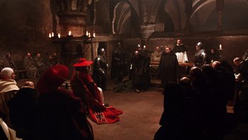Movie still from “The Name of the Rose” (1986), directed by Jean-Jacques Annaud – A group of people standing around a room; Wide shot, High angle