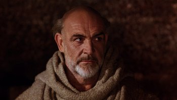Movie still from “The Name of the Rose” (1986), directed by Jean-Jacques Annaud – An older man with a beard and a scarf around his neck; Close Up shot, Low angle