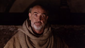 Movie still from “The Name of the Rose” (1986), directed by Jean-Jacques Annaud – A man with a gray beard wearing a brown blanket; Close Up shot, Low angle