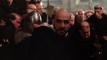 Movie still from “The Name of the Rose” (1986), directed by Jean-Jacques Annaud – A group of men in a crowd of people wearing helmets; Close Up shot, Low angle