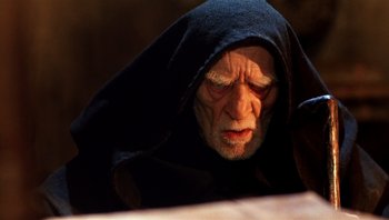 Movie still from “The Name of the Rose” (1986), directed by Jean-Jacques Annaud – An old man wearing a black robe and a hood; Close Up shot, Over the shoulder angle