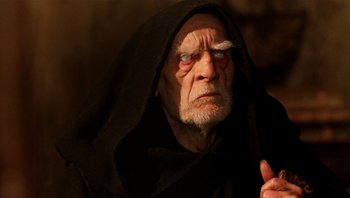 Movie still from “The Name of the Rose” (1986), directed by Jean-Jacques Annaud – An old man wearing a black hooded robe; Close Up shot, Over the shoulder angle